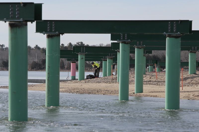 A welder is framed by the beams he is attaching to the posts, as work continues on building a new elevated walk/bike path which runs from Depot Street to the back of the YMCA in Mattapoisett, MA. over a river and mash land.   PHOTO PETER PEREIRA