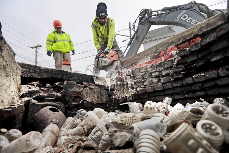 New Bedford DPI pipefitters, Kevin Sylvia and Jacob Levalley, prepare the opening of a catch basin at the intersection of Roosevelt Street and Cove Road for a new Bradley head.  In the basin, hundreds of plastic bottles are seen floating above the water, causing drainage problems when heavy rains sweep across the region.  PHOTO PETER PEREIRA