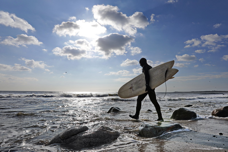 Miles Potter heads into the water to take advantage of an unexpected swell that brought surfable waves to east beach in Westport, MA.  PHOTO PETER PEREIRA