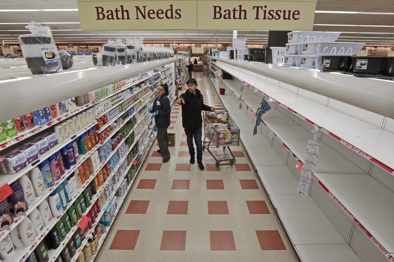 Market Basket grocery clerk, Helena Brosius, helps a customer find soap, while on the other side of the isle, the shelves which normally contain toilet paper and other paper goods are completely empty at Market Basket in New Bedford, MA. PHOTO PETER PEREIRA