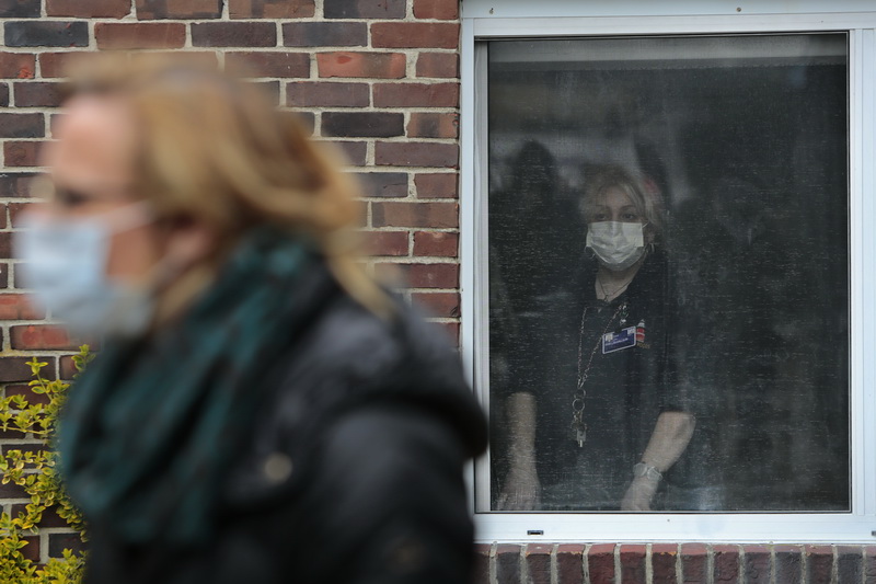 A worker from inside the facility looks on as mayor Jon Mitchell announces the establishment of the conversion of two former nursing homes into regional care centers for COVID-19 patients.  The press conference was held in front of the former Kindred Nursing and Rehabilitation facility on Rockdale Avenue in New Bedford, MA. PHOTO PETER PEREIRA