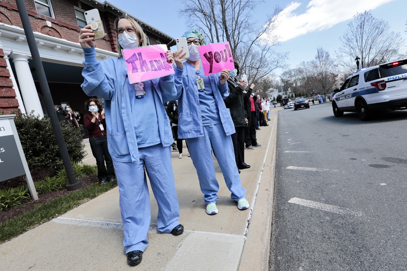 Labor/Delivery nurses Jillian Heos and Rhonda Chicoine thanks New Bedford Police officers as they along with New Bedford firefighters drive past the entrance to the emergency room at St. Luke's Hospital in New Bedford, MA as a show of support for healthcare workers. PHOTO PETER PEREIRA