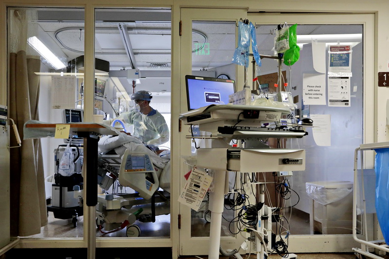 Dr. Michael Barretti, checks on the ventilator of a COVID-19 patient in critical condition inside one of the sealed rooms of the St. Luke's Hospital ICU in New Bedford, MA.  PHOTO PETER PEREIRA