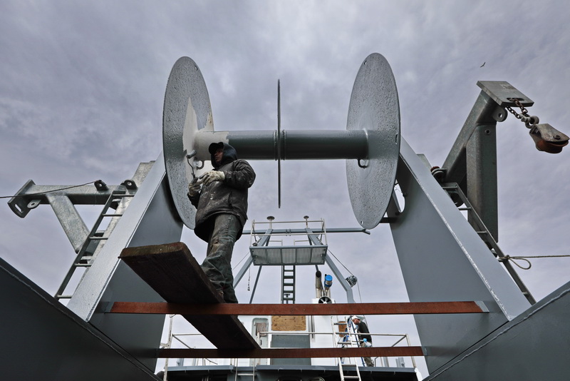 Domingo Tam applies a coat of primer on the net drum on a fishing boat in New Bedford, MA.  PHOTO PETER PEREIRA