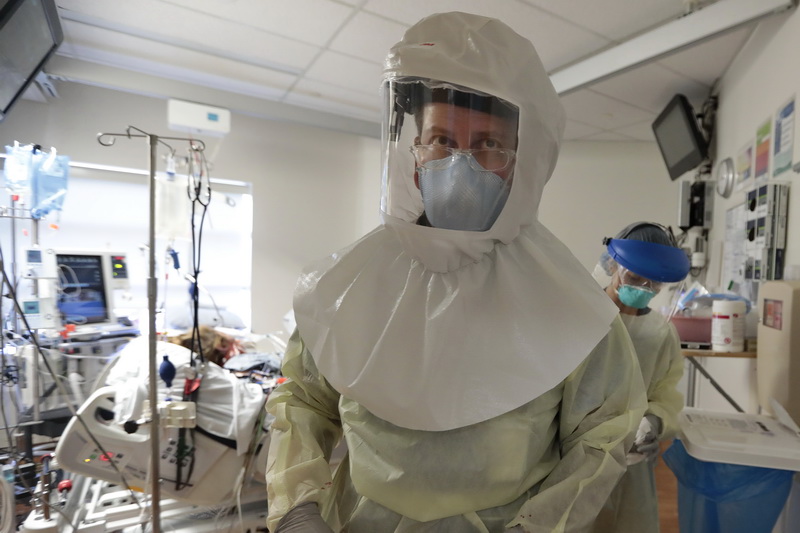 Wearing a PAPR hood, Dr. Hector Mateo keeps his eyes on the screen after intalling a dyalisis cathoder in a COVID-19 positive patient at the Charlton Memorial Hospital in Fall River, MA.  PHOTO PETER PEREIRA