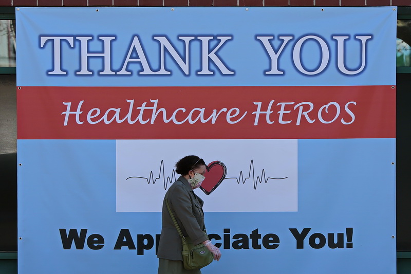 A woman walks past a sign hanging in front of the Greater New Bedford Community Health Center and Wallgreens Pharmacy on Purchase Street in downtown New Bedford, MA.  PHOTO PETER PEREIRA