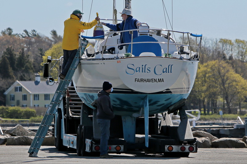 Two men prepare to put their aptly named sailboat 'Sails Call', into the water in Mattapoisett, MA harbor as the boating season begins ramping up.  PHOTO PETER PEREIRA