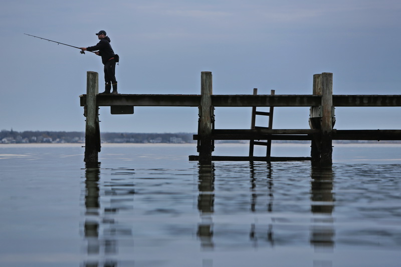 A man casts his line from a pier in the south end of New Bedford, MA on a perfect morning.  PHOTO PETER PEREIRA