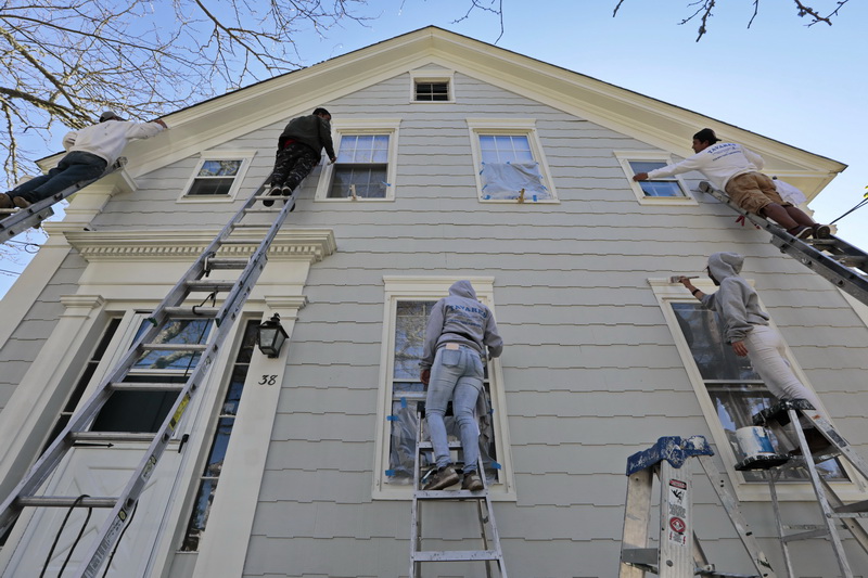 A crew achieves multi-dimensional levels of efficiency, as they paint the front of a home in Mattapoisett, MA.  PHOTO PETER PEREIRA