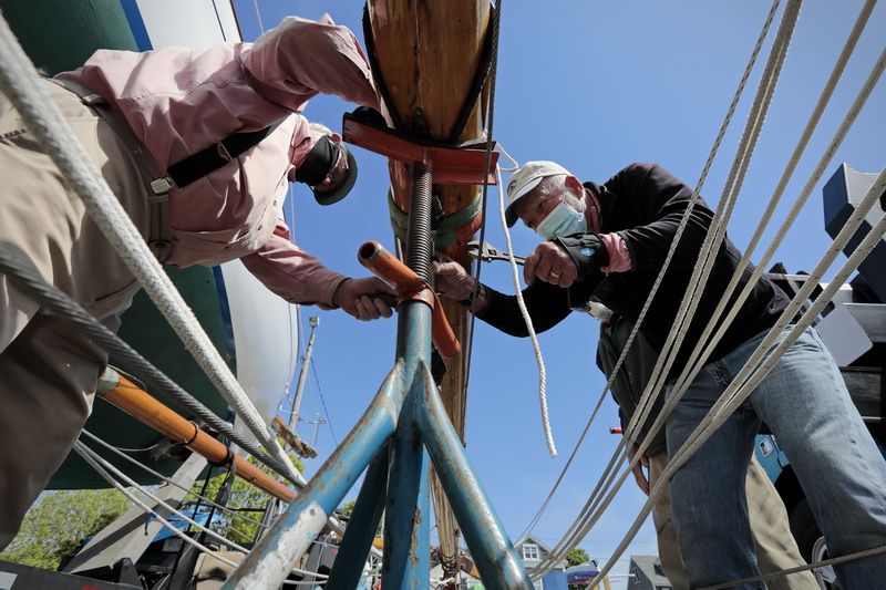 Rick Sears and Peter Lawrence work on rigging the mast of their boat 'Aeolus' before putting it in the water for the first time this season in Mattapoisett, MA.   PHOTO PETER PEREIRA