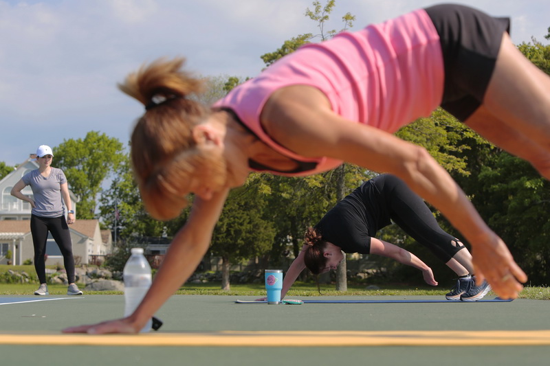 Personal trainer, Braley Freire keeps an eye on Nicole Antonio and Michelle Senna, as they perform modified planks during Outdoor Boot Camp at Fort Phoenix in Fairhaven, MA.  Because Braley she is not able to open her gym, B. Balance Fitness in Fairhaven due to the COVID-19 pandemic, she has brought personal training sessions outdoors, and applied the proper distancing which the space gives her.  PHOTO PETER PEREIRA