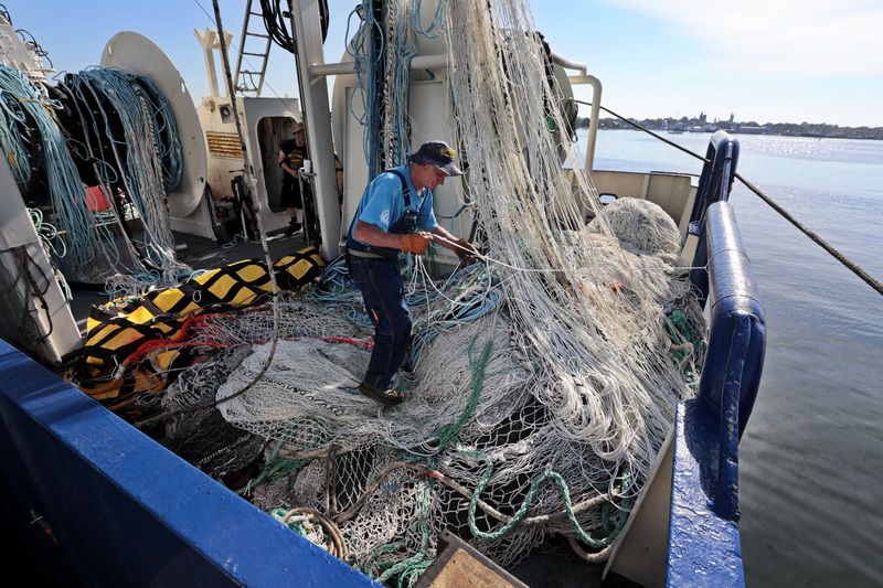 Enda Mullen works on repairing the squid nets of the fishing boat Enterprise docked at State Pier in New Bedford, MA.  PHOTO PETER PEREIRA