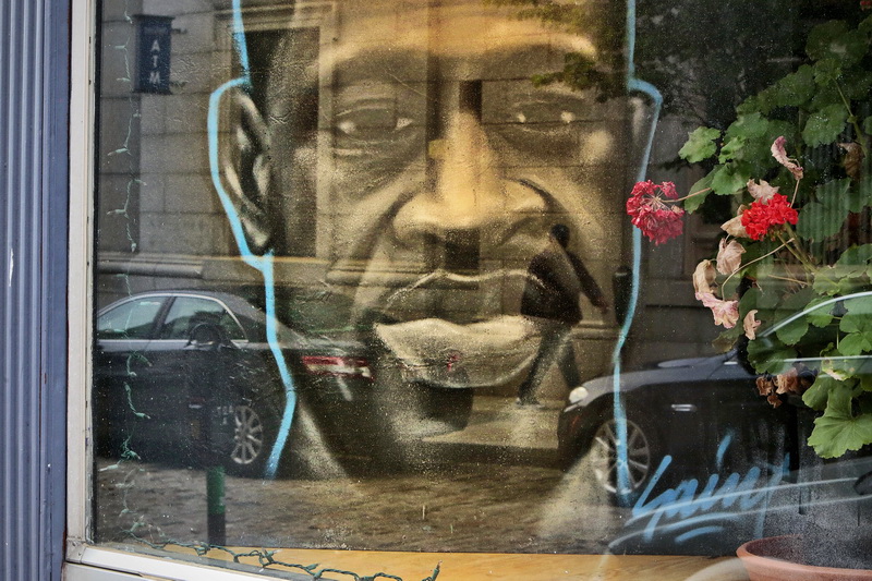 A man walking up William Street in New Bedford is reflected from the gallery window in front of a portrait of George Floyd painted by local graffiti artist Jeff St.Pierre seen inside the Paradise McFee Gallery.  PHOTO PETER PEREIRA