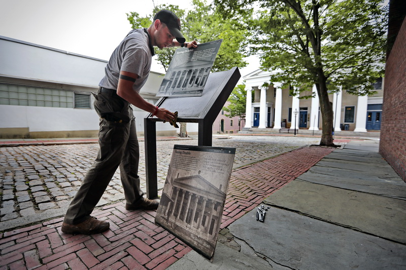 Mike Turdo of the National Park Service, replaces the sign outlining the long history of the JJ Best Banc& Co. building at the bottom of William Street in New Bedford, as part of the replacement of all historical signs downtown.   PHOTO PETER PEREIRA