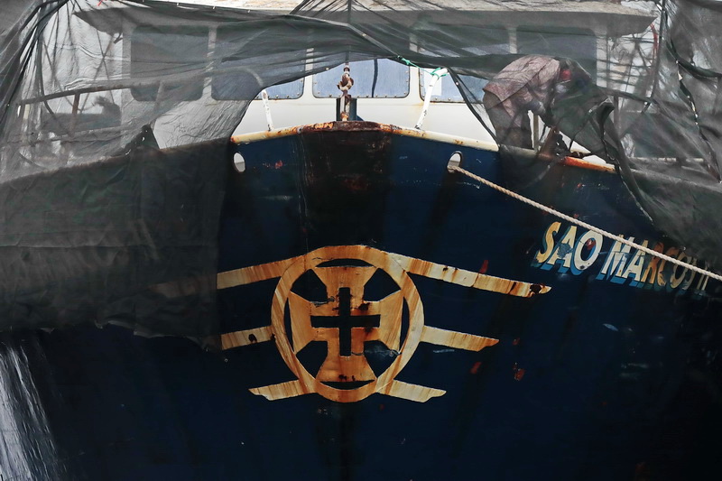 A painter is seen behind the temporary dust protection sheet as he removes the old rusty sections from the Sao Marcos II fishing boat docked in New Bedford, MA before applying a fresh coat of paint.   PHOTO PETER PEREIRA