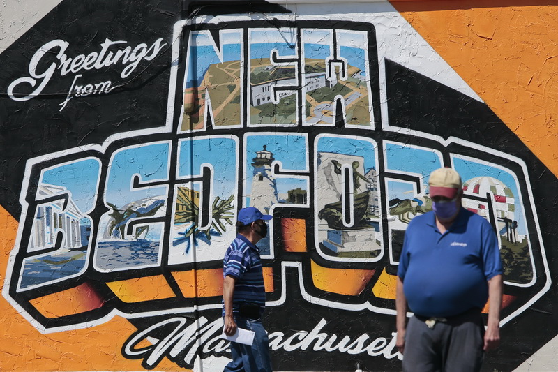 Two men walk past the Greetings from New Bedford mural recently finished at the Bank of America parking lot on Elm Street in downtown New Bedford, MA.   PHOTO PETER PEREIRA