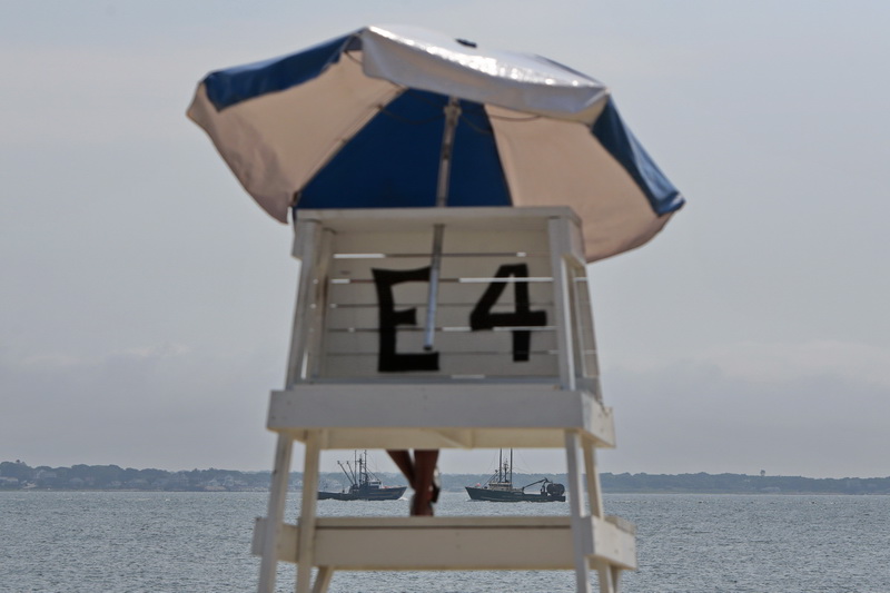 A lifeguard watching East Beach in the south end of New Bedford, MA looks on as a fishing boat heads out to sea, while another returns to port. PHOTO PETER PEREIRA