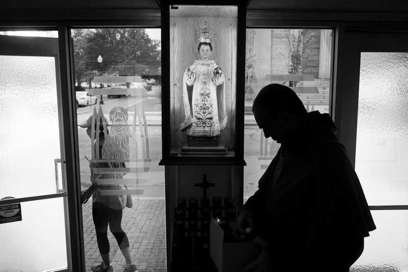 A parishoner leaves as Franciscan friar, Father Andre Feain, replaces the votive candles under the reproduction of a Bulgarian Jesus statue said to have healing powers, at the entrance of Our Lady's Chapel in downtown New Bedford, MA. PHOTO PETER PEREIRA