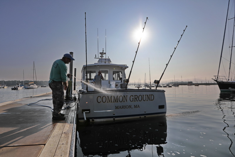 Bill Hullbig helps his friend Eric Dhedouville clean off his boat 'Common Ground' docked in Marion harbor, after arriving from a tuna catching excursion, and before Mr. Dhedouville heads back out for a day of boating with his wife.   PHOTO PETER PEREIRA