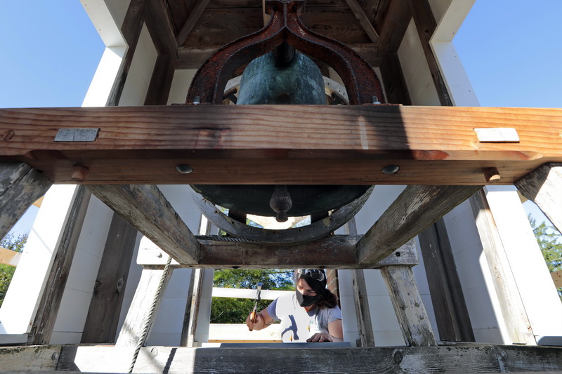 The bell of the Bell School House looms above, as Amanda Gray of Heritage Restoration works on restoring the steeple of the school built in 1841 on Drift Road in Westport, MA. The Bell School House currently houses the Westport Historical Society.  PHOTO PETER PEREIRA