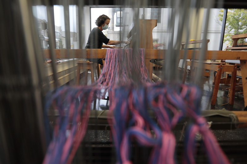 Former textile professor (who just retired a few months ago after over 20 years of teaching) works on a loom making a two-sided weaving piece to be shown to students by the graduate student who is teaching the complex weaving class at UMass Dartmouth in downtown New Bedford, MA.  PHOTO PETER PEREIRA