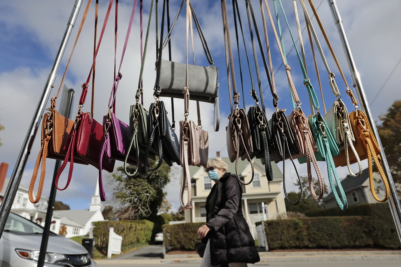 A woman walks past some for custom hand bags for sale hanging from a rack outside of Shara Porter Hand-Printed Accessories on Elm Street in Padanaram village Dartmouth, MA.  PHOTO PETER PEREIRA