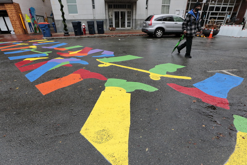 A pedestrian makes his way across Purchase Street in downtown New Bedford, MA on a new colorful crosswalk painted with feet walking and skateboarding.  PHOTO PETER PEREIRA