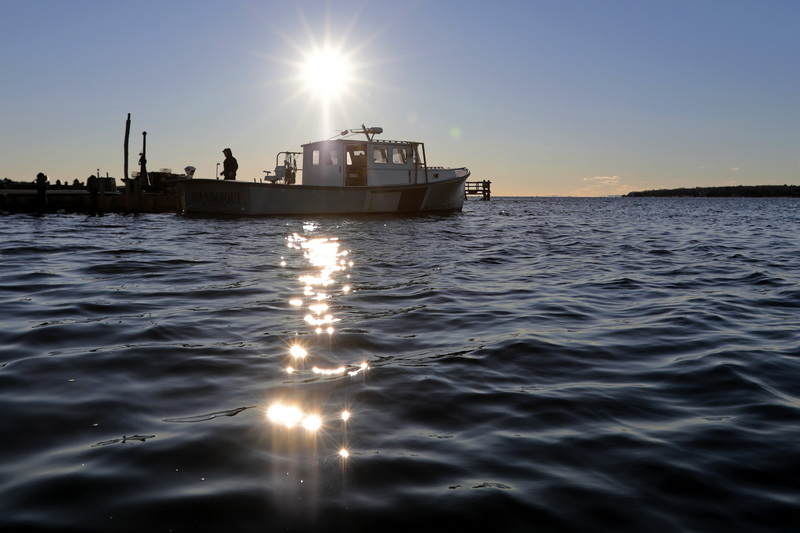 The sun rises in the distance as a fisherman prepares to pull his lobster boat out of the water in Mattapoisett, MA. PHOTO PETER PEREIRA 