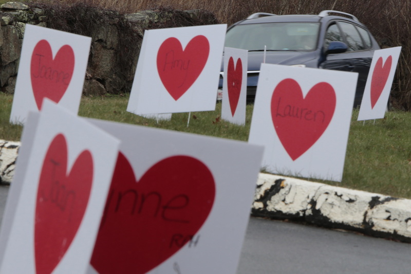 A car driving up Main Road in Westport, MA passes a series of heart signs in front of Westport Apothecary.  The signs are part of the 'Westport Has a Heart Fundraiser