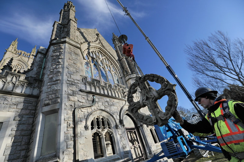 Pauly Reed of Cenaxo, handles the west facing Celtic cross, as it is lowered after he removed it from the top of the Unitarian Church in Fairhaven.  This is one of two crosses being restored at the iconic church in Fairhaven, MA.  PHOTO PETER PEREIRA