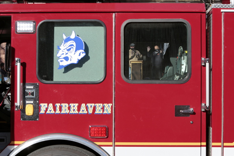 Fairhaven Fire Department Chief, Timothy Francis, waves to those in attendance in front of Fairhaven Town Hall, after receiving a plaque from Chairman of the Board of Selectmen, Daniel Freitas, celebrating 42 years of service, as seen through the window of Ladder One which he took for a final ride around town. PHOTO PETER PEREIRA