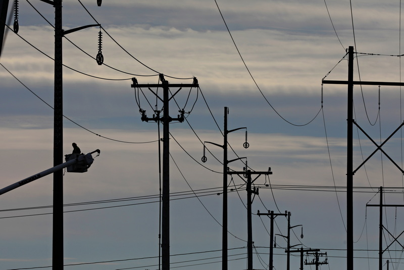 A line installer is seen high above the ground, as new high-voltage utility poles are installed in Dartmouth, MA.  PHOTO PETER PEREIRA