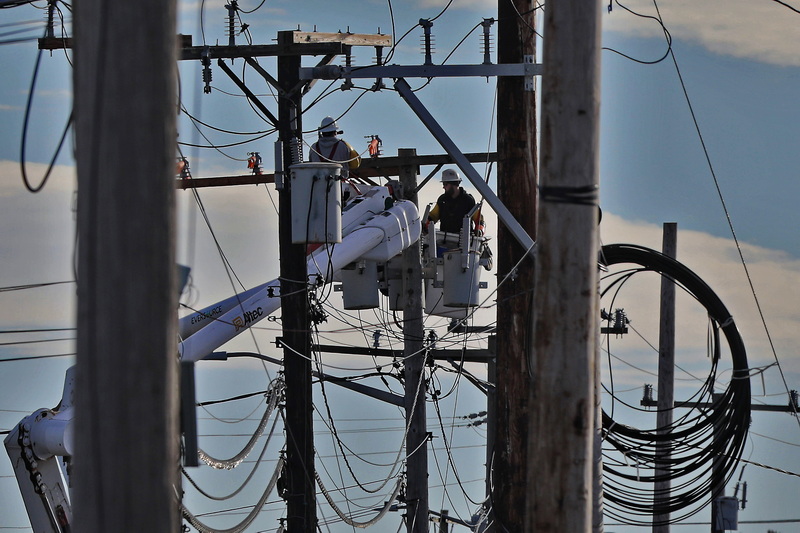 Workers are surrounded by wiring as they replace the existing utility poles lining Route 6 in Wareham, MA with new ones.  