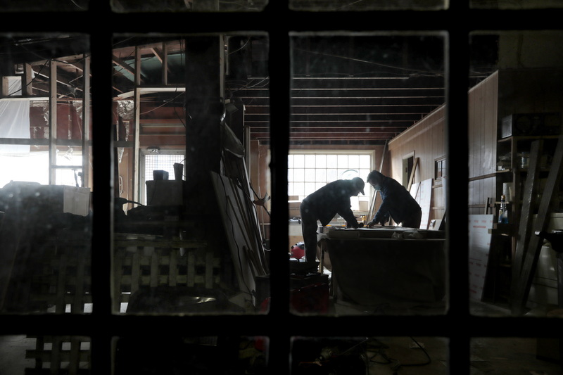 Chuck Rooney and his son Ryan Rooney work on creating custom COVID partitions, for the soon to open newly renovated Cultivator Shoals on Union Street in New Bedford, MA as seen through salvaged glass French doors.   PHOTO PETER PEREIRA