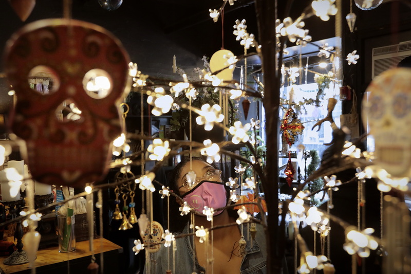 Alyssa Medeiros takes a look at some of the items for sale hanging from a tree of lights at Sanctum Folklorica on Purchase Street in New Bedford, MA which recently re-opened after a long closed spell due to the ongoing pandemic. PHOTO PETER PEREIRA