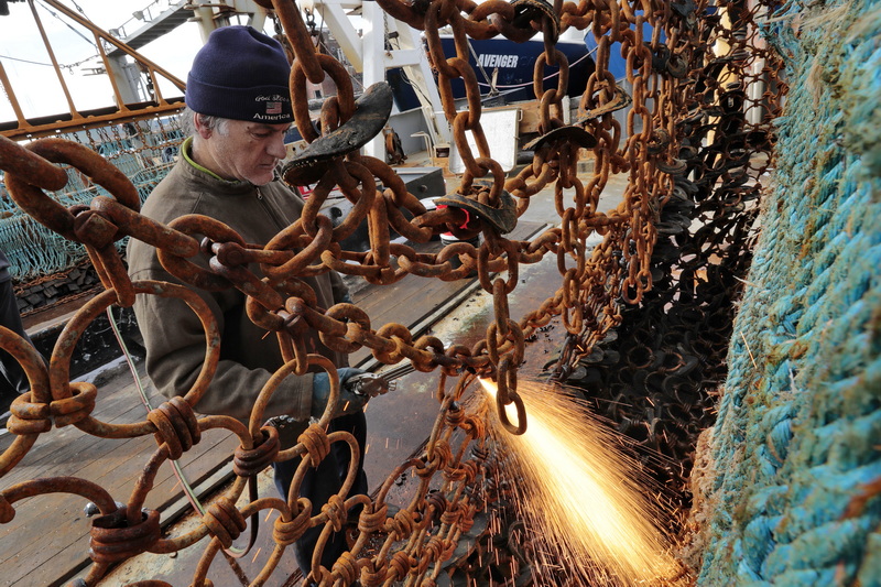 The mate of the Lady of Fatima fishing boat, Antonio Vicente, cuts the broken links of the dredges on the New Bedford scalloper, in preparation to heading back out to sea next weekend.  PHOTO PETER PEREIRA