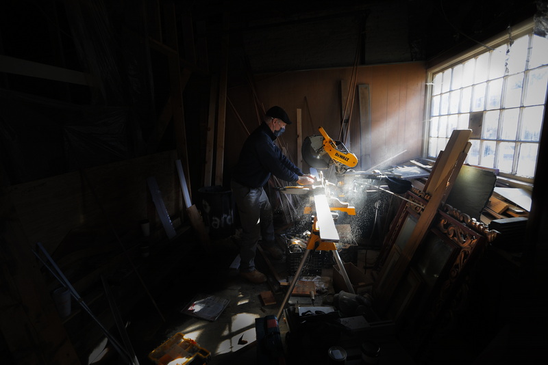 Rays of light coming through the window are caught by the sawdust as Chuck Rooney cuts a piece of wood for a bar he is making for the soon to open Cultivator Shoals on Union Street in New Bedford, MA.  PHOTO PETER PEREIRA