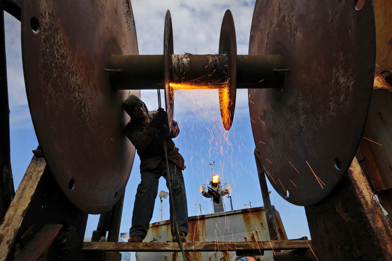 Manuel Franco sends sparks flying as he uses a cutting torch to remove the two inner disks of a giant drum on board the fishing vessel Sao Paolo docked in New Bedford, MA.  The drum is where the fishing nets are rolled up when not being used. PHOTO PETER PEREIRA