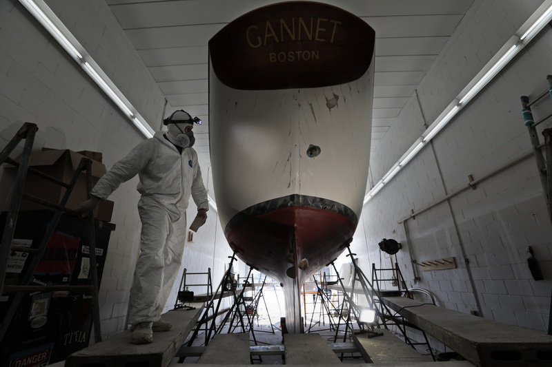 Bill Knapton uses a headlight to check which sections of the sailboat he is working on need additional sanding, inside one of the paint booths at Triad Boatworks in Mattapoisett, MA. PHOTO PETER PEREIRA