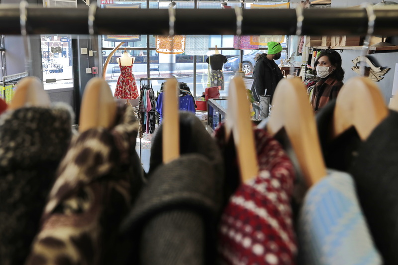 Kay Lynne is seen through the coat rack at her store, The Mad Lila, on Puchase Street in downtown New Bedford, as a customer looks through the many items for sale.  Throught he other gapes between the hangers other dresses can be seen. PHOTO PETER PEREIRA