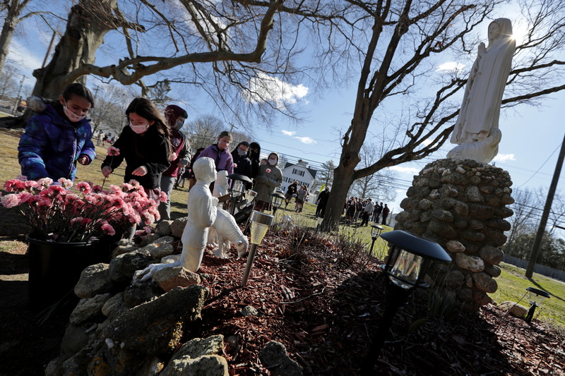 Students of the St. Francis Xavier school in Acushnet place pink carnations in front of a statue of Marie, to honor Therese Ledoux (the school's kindergarten teacher for thirty years) as her funeral motorcade drove by.  Mrs. Ledoux was 103 years old when she passed away last week, and was a regular presence at the Acushnet school long after she retired. PHOTO PETER PEREIRA