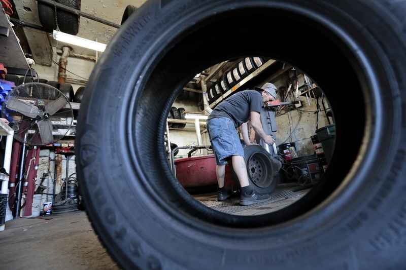 A new tire is seen in the foreground, as Russell Santos removes the existing tire from the wheel in the background at Joe's Tire on Acushnet Avenue in the north end of New Bedford, MA. PHOTO PETER PEREIRA