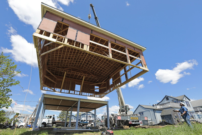 Workers from A1 Crane in Fairhaven, lift an entire house, which was built on the ground, to place on the newly finished elevated foundation in Westport, MA. PHOTO PETER PEREIRA