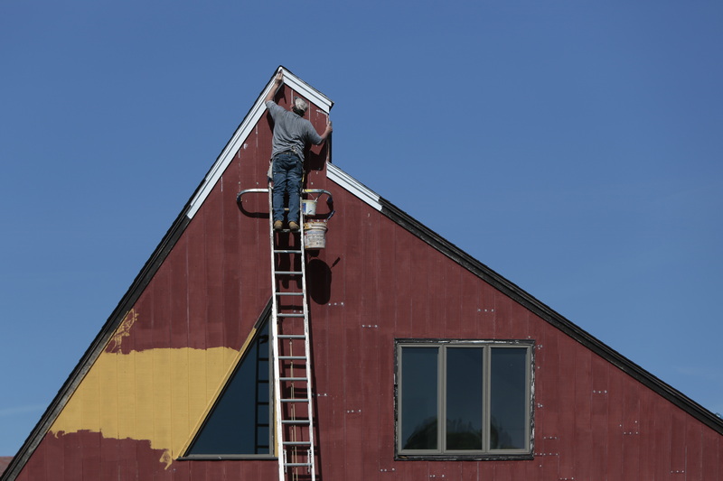 Barry applies a fresh coat of paint to trim at the very top of a home he is re-painting in New Bedford, MA.  PHOTO PETER PEREIRA