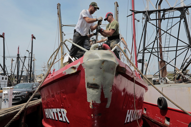 Crewmembers of the Hunter, adjust the tension of the steel cable that runs from the mast to the bow of the New Bedford fishing boat. PHOTO PETER PEREIRA