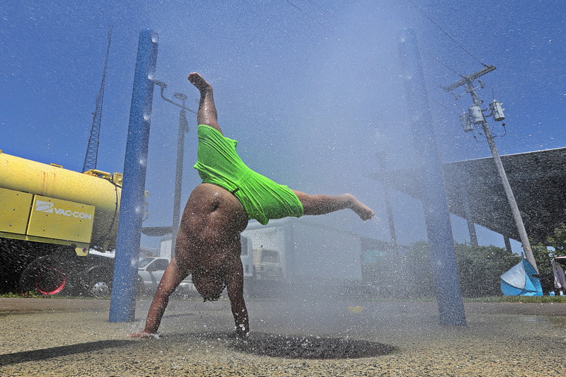 Elijah Garcia, 7, takes shelter from the sweltering heat, by playing at the sprinkler station at Ben Rose Park in New Bedford, MA. PHOTO PETER PEREIRA