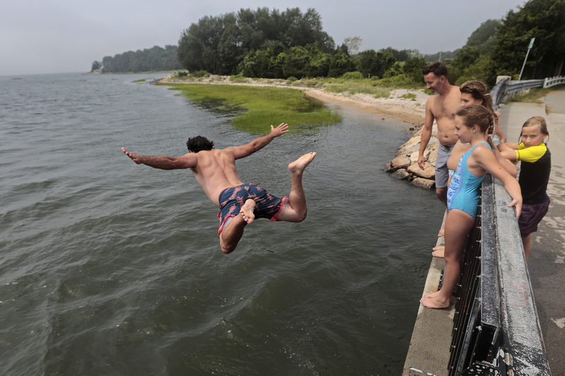 (top) A man helps some youngsters with the bait on their line, as they enjoy a morning of fishing from a pier in the south end of New Bedford.  In the distance the Seastreak high speed ferry can be seen making its way to Martha's Vineyard. (below) Young and old alike, take shelter from the heat by jumping off of the Little River Road bridge in Dartmouth, MA.  PHOTOS PETER PEREIRA