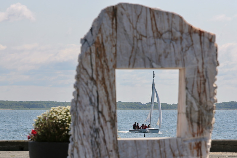 Youngsters sailing are seen through a granite sculpture insalled at a pier in the south end of New Bedford, MA.  PHOTO PETER PEREIRA