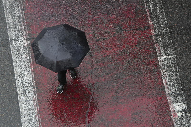 A pedestrian makes his way across the red crosswalk on Elm Street in New Bedford, MA on a rainy morning, as seen from the top of the parking garage.  PHOTO PETER PEREIRA