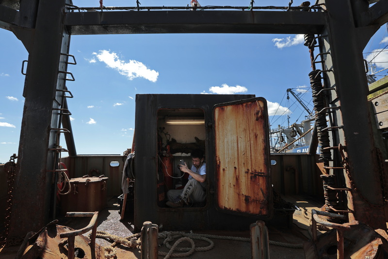 Bao Nguyen finds a quite space inside a storage room at the back of the fishing boat, to conduct a video call with his family, before he and fellow crewmembers of the scalloper Santa Isabel cast off on a twelve day fishing trip from New Bedford harbor.  PHOTO PETER PEREIRA